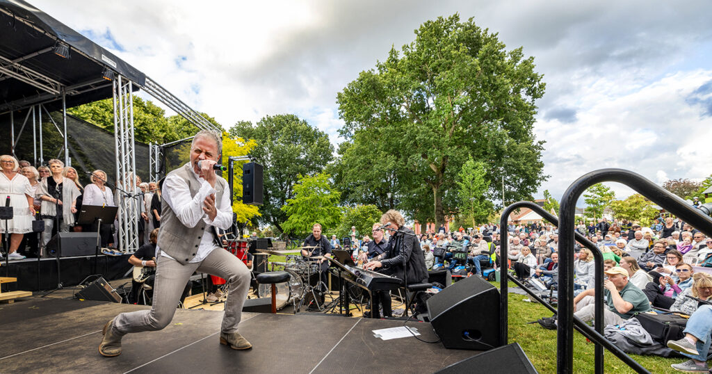 Glenn på scen med musiker i bakgrunden.