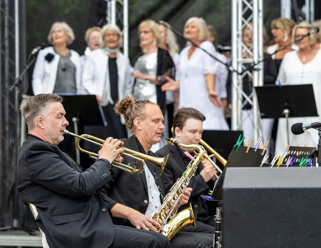 Trumpetare och saxofonist med kören i bakgrunden.